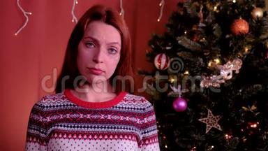 一个红头发的年轻女人看着相机，圣诞节时很难过。 背景中的圣诞树。 概念